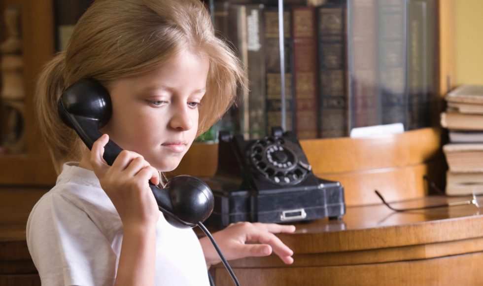 Closeup of a cute blond girl using telephone at home
