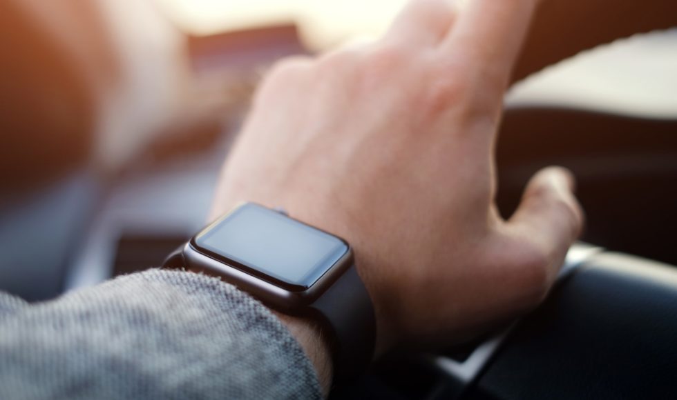 man driving a car with smart watch on the hand