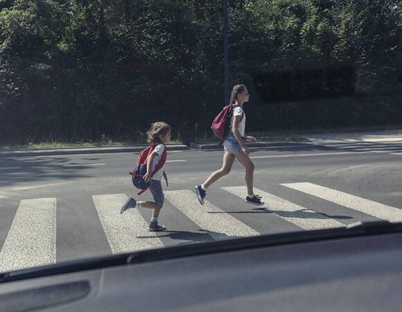 View from the car on children running on pedestrian crossing